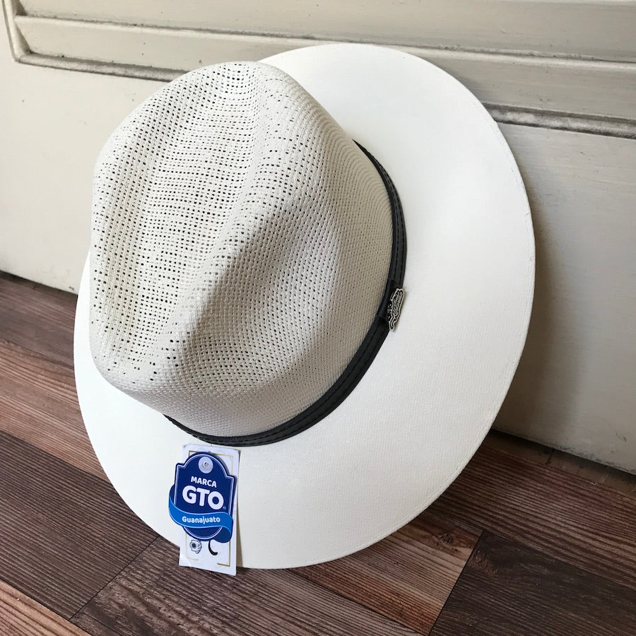 A handcrafted beige fedora hat with a black leather band, displayed on a flat surface, with a tag indicating authenticity and Mexican craftsmanship.