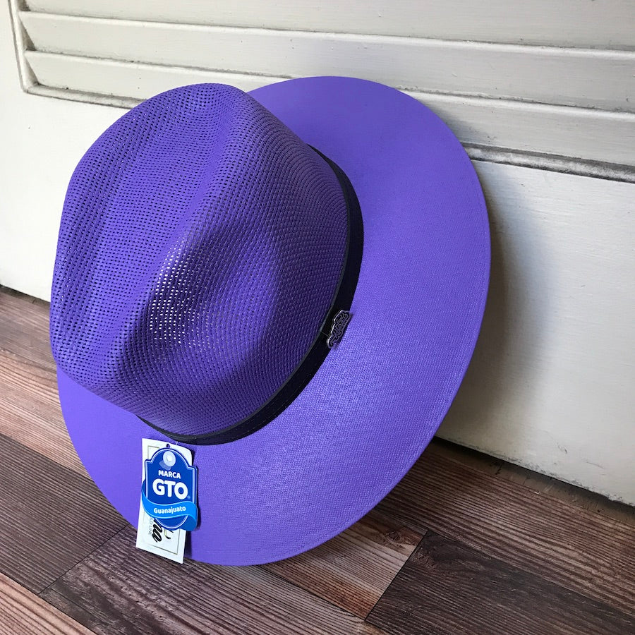 A purple straw hat with a leather band, placed on a wooden surface, with a visible GTX label on the brim.